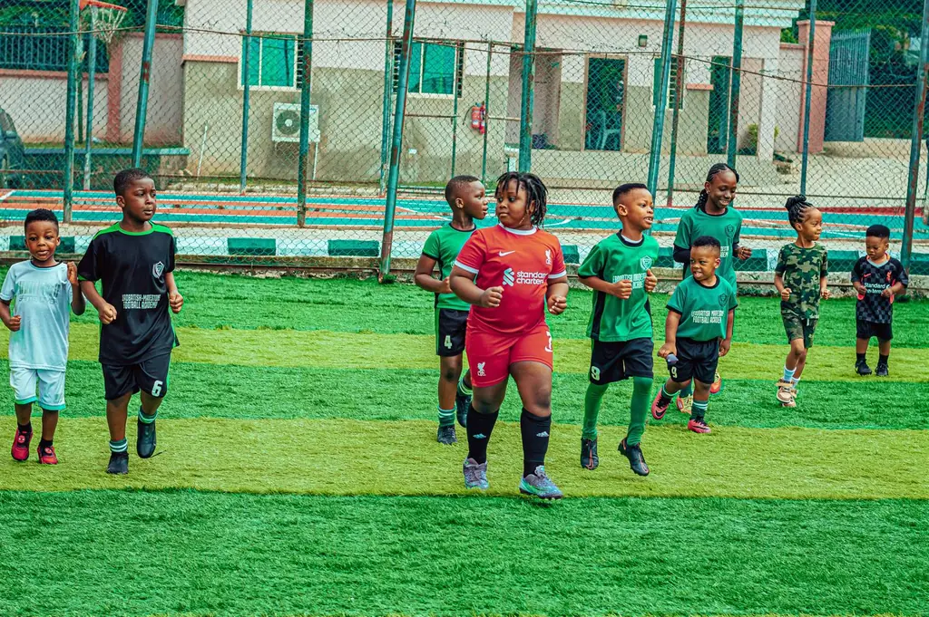 A group of smiling children jogging together during a Madestone warm-up