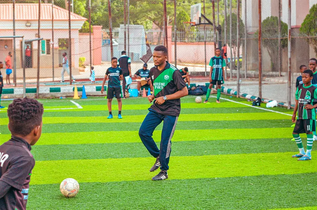 Coach demonstrating close control to young players during a Madestone session