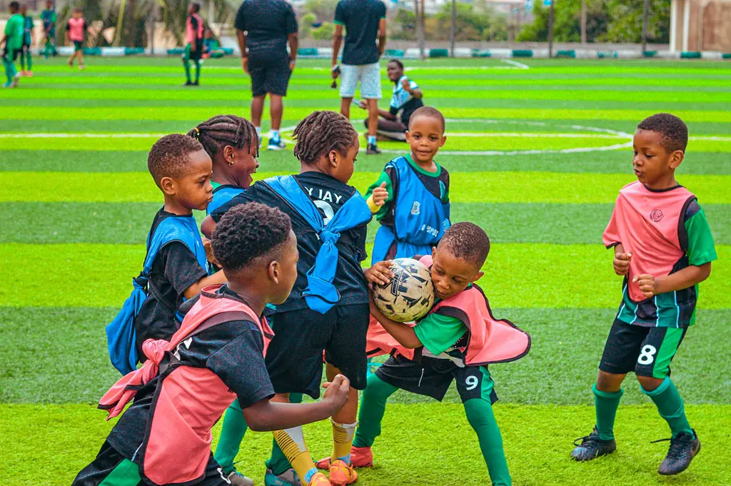 Children in training bibs competing for the ball in a small-sided game