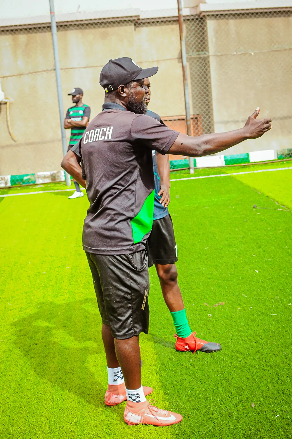 A Madestone coach gesturing while explaining a drill on the pitch