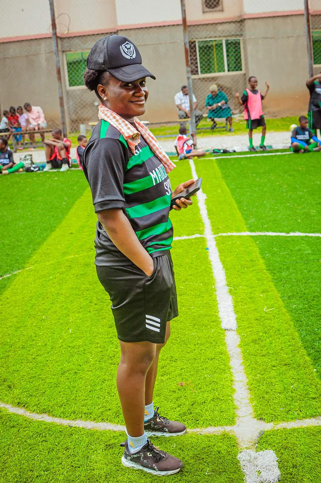 A coach standing on the touchline watching a training session