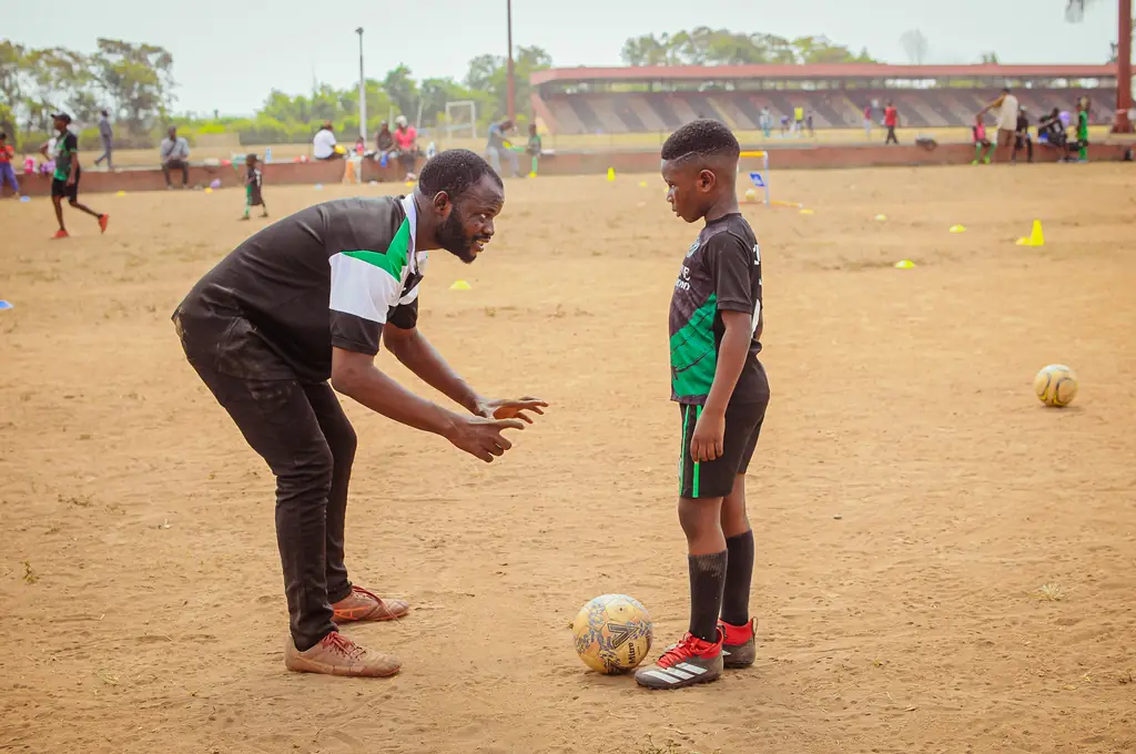 A coach working one-to-one with a young player on ball technique